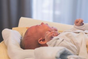 Baby yawning ,lying down facing upwards.