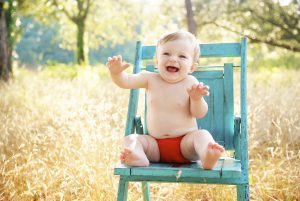 Happy and healthy baby sitting on a chair in the outdoors.