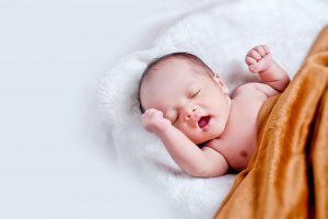 Newborn baby sleeping on a bed in How often to bathe newborn