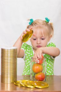 Baby stacking apples in a container.