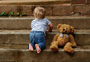 baby crawling up the stairs with teddy bear.