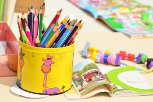 A tin of baby crayons and some story books  in Infant activities for daycare