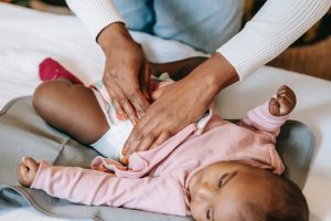 mother changing baby diaper in How many newborn diapers do I need