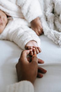 baby holding on to mother's finger; in How many newborn diapers do I need