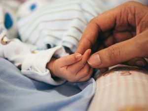 Baby hand and adult hand in how to file baby nails.