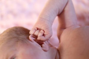 Baby with hand on ear in How to get toddler to stop biting nails.