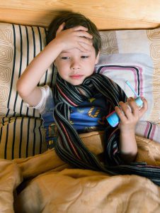 sick child lying in bed with runny nose medicine