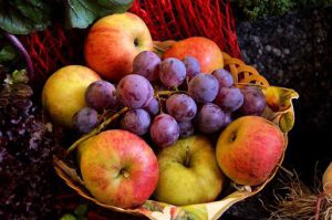 Ripe fresh purple grapes with green and red apples in a basket.